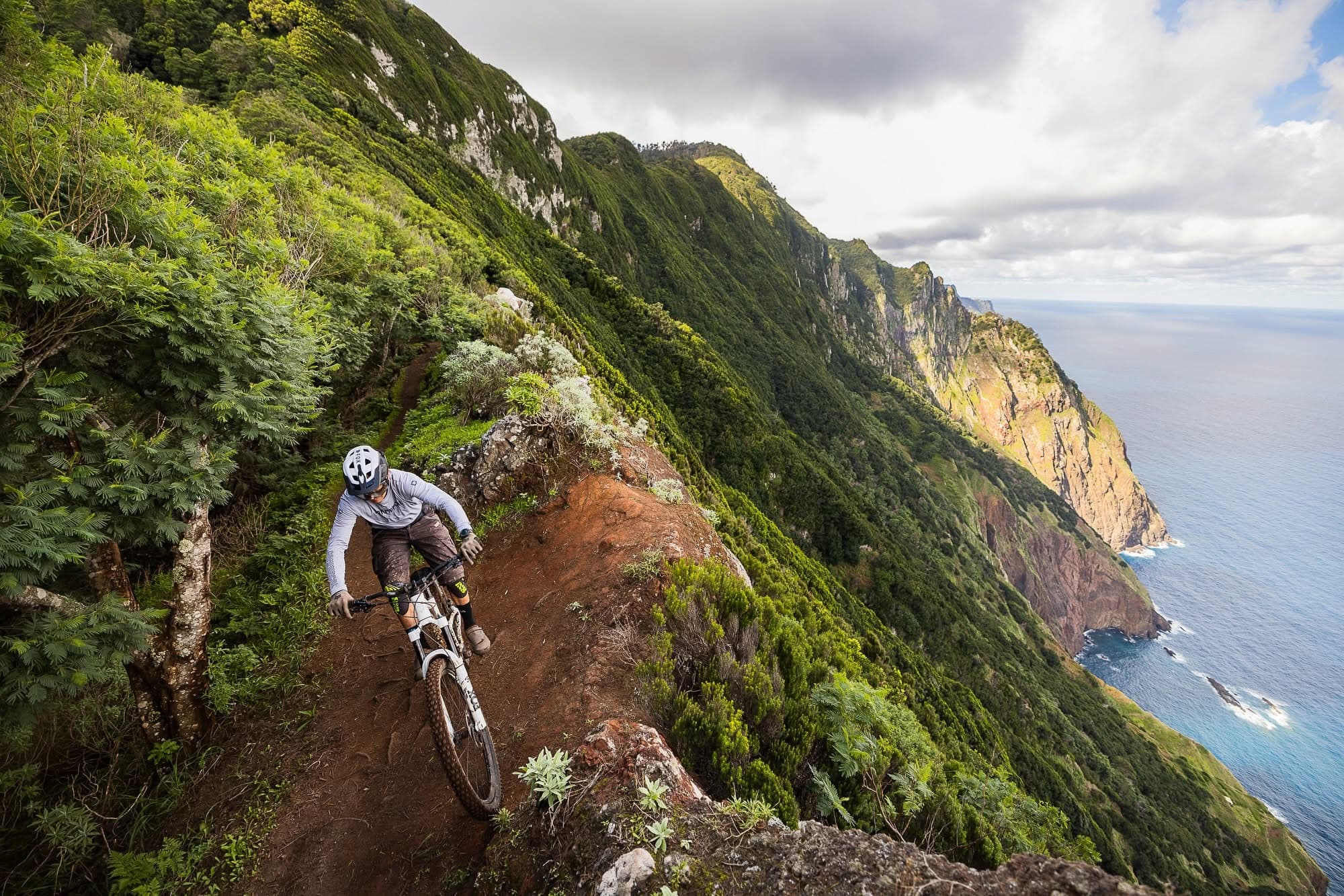 A rider on a narrow clifftop trail above the sea