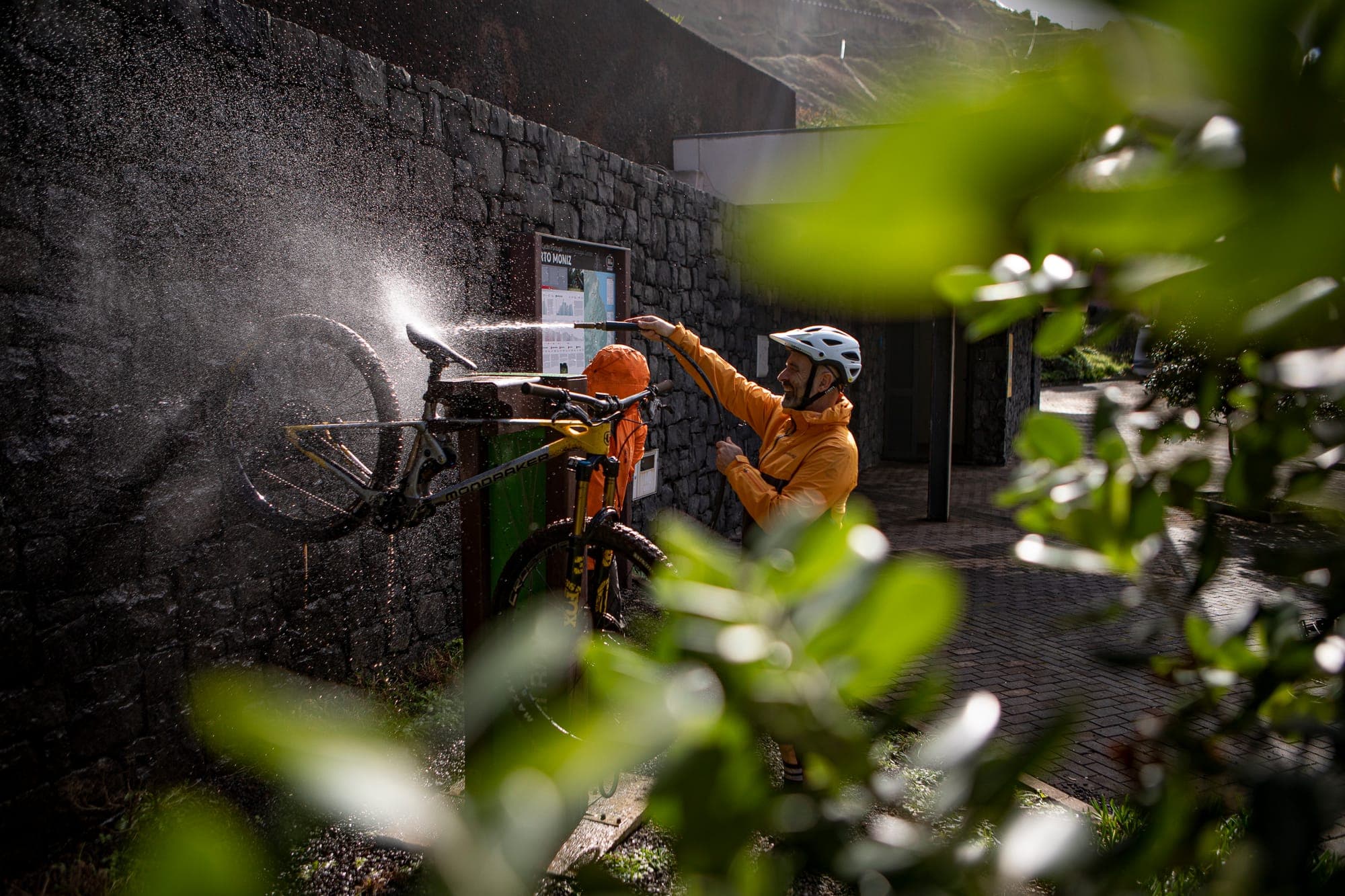A rider washing a mountain bike at a trail-head wash station after a ride