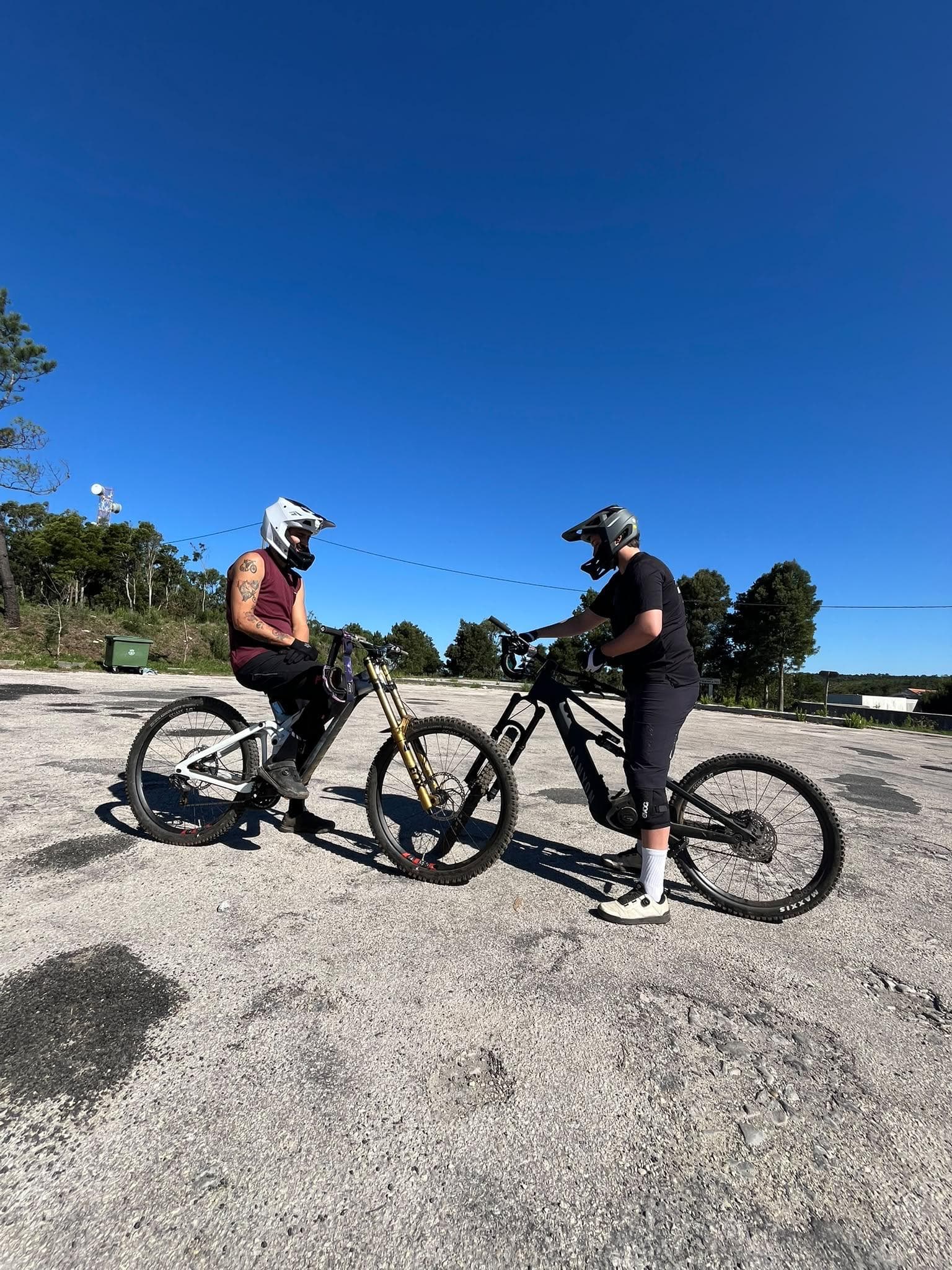 Two mountain bikers in full-face helmets talking before a ride